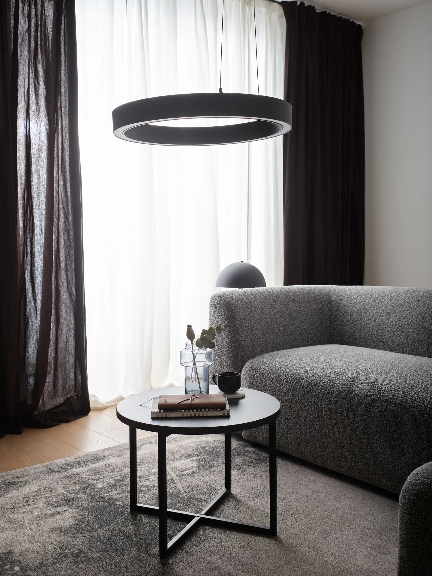 Szara sofa i okrągła lampa